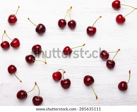Fresh juicy cherries on the white wooden background, top view