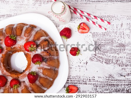 Delicious glazed cake with strawberries on white wooden table, top view.