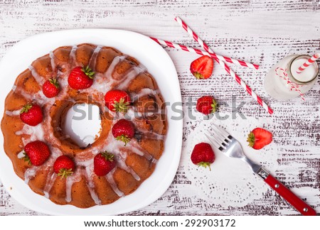 Delicious glazed cake with strawberries on white wooden table, top view