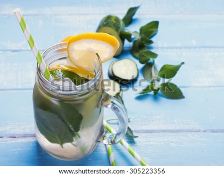 Lemon cucumber detox water in glass jar on blue colored wooden table close-up