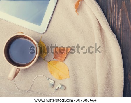 Autumn morning. Cup of coffee, tablet, earphones and warm blanket, top view. Toned photo.