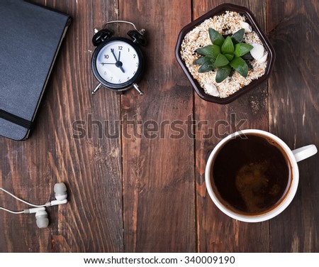 Coffee, alarm clock, succulent plant and earphones on the wooden table, top view