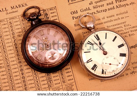 Two antique pocket watches on antique hall mark guide.