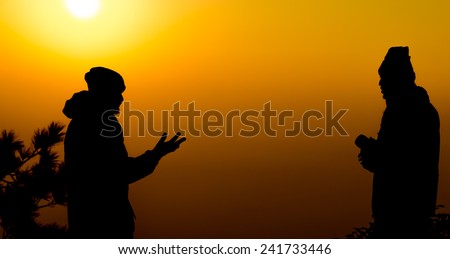 two man talking or communication in silhouette in warm tone sky