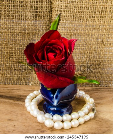 element design of red rose and pearl on wooden floor and sack texture background ,vintage ,still life