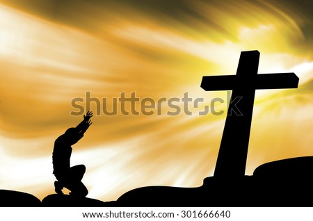 praying man with black cross silhouette in rocks over a  sky