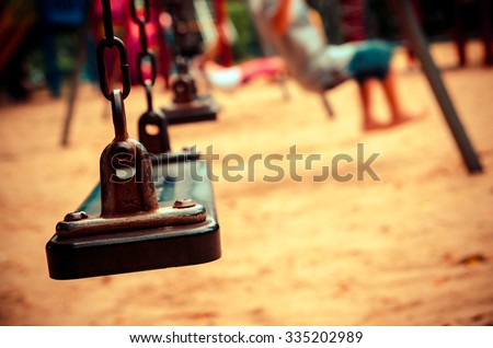 chain swings on playground with blur kid on park , vintage tone color