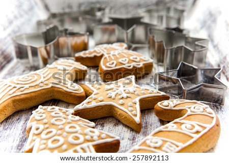 Icing decorated gingerbread cookies with selection of metal cookie cutters on white painted grunge style wooden table