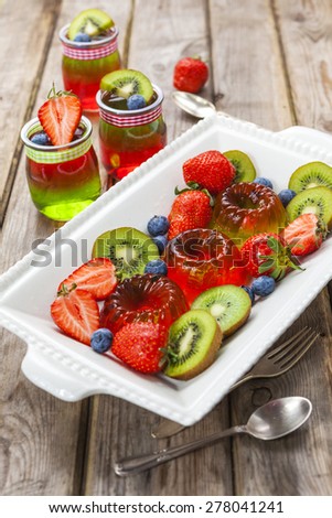 Red and green jelly served with fruit on the rustic wooden table