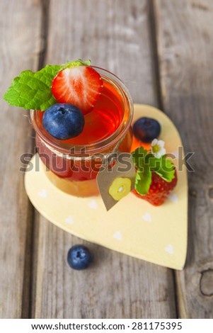 Red and yellow jelly in jars served with fruit on the rustic wooden table