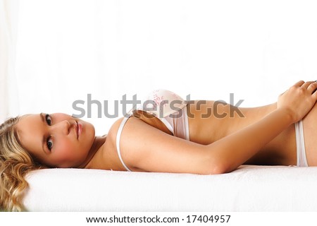 The charming girl laying on beds looks at the spectator