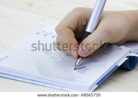 pen in hand writing on the notebook