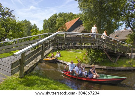 GIETHOORN, NETHERLANDS - AUGUST 05, 2015: Unknown visitors in the sightseeing boating trip in a canal in Giethoorn. The beautiful houses and gardening city is know as \