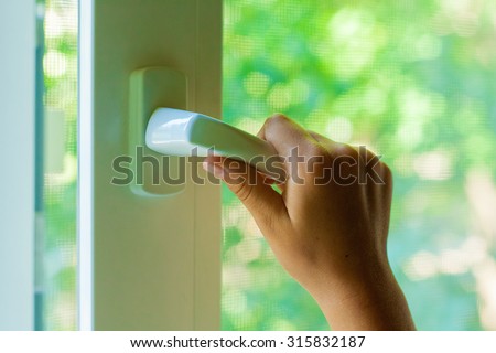 Child\'s hand opens a plastic window closeup