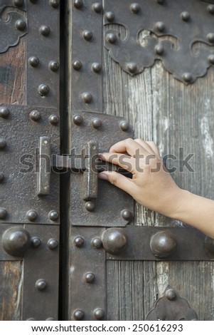 Photo of female hand putting house key into front old door lock of house