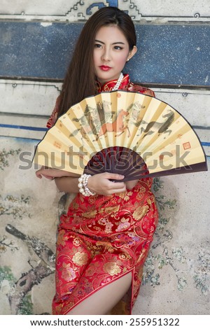 Beautiful Asian girl with Chinese traditional dress Cheongsam holding a Chinese Fan