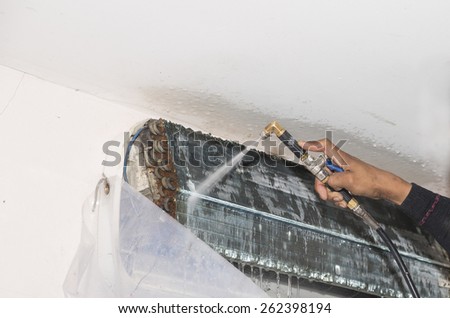 Repairman fixing and cleaning air conditioner unit