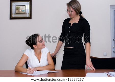 Two women at the office signing papers