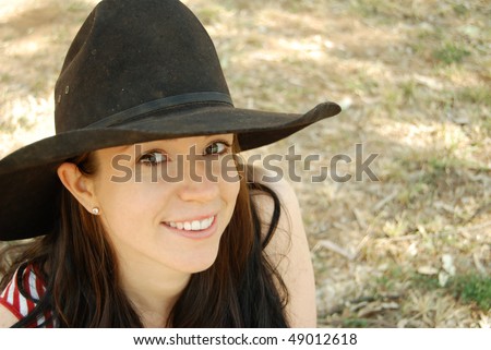 Beautiful country woman in a cowgirl hat outdoors
