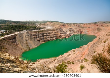 Emerald green lake in flooded opencast mine, open pit. Oval lake in mining industrial crater, acid mine drainage in rock. Open pit mine with lake. Quarry fluxes for the industry.