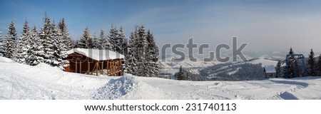 Ski mountains panorama, track, wooden building under snow, firs, lift, hills, sunny weather