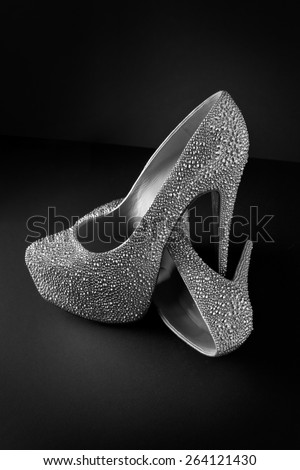 Crystal studded high heel shoe with platform on black background. One shoe is standing and the other shoe is lying beneath the other shoe.