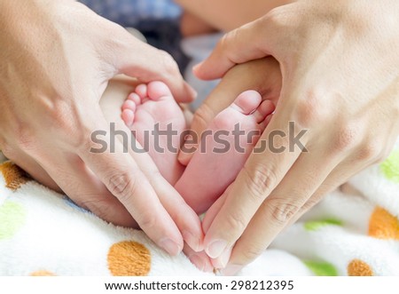 newborn baby feet on mom and dad hands, shape like a lovely heart