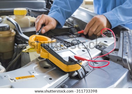Car repair service, Auto mechanic checking a car battery level by voltmeter