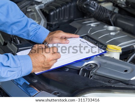 Car repair service, Auto mechanic checking car engine, writing checklist on clipboard