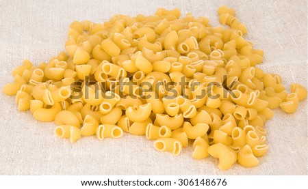 the yellow short scattered macaroni on a beige cloth from rough fabric