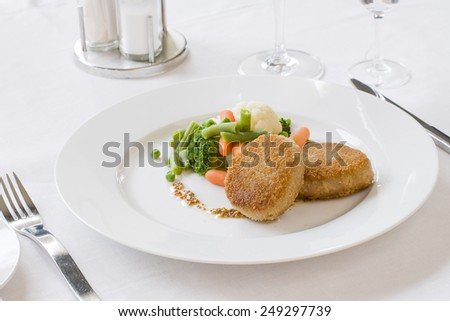 Fried cutlet with a side dish of raw and cooked vegetables on a white plate
