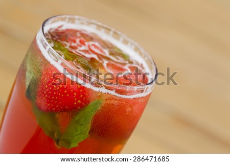 Cold lemonade with strawberries, mint and ice on the outdoor veranda summer day, sunlit.