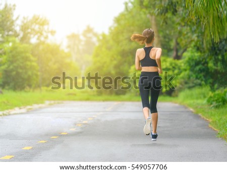 Young fitness sport woman running on the road in the morning, Sun light flare , Selective focus.