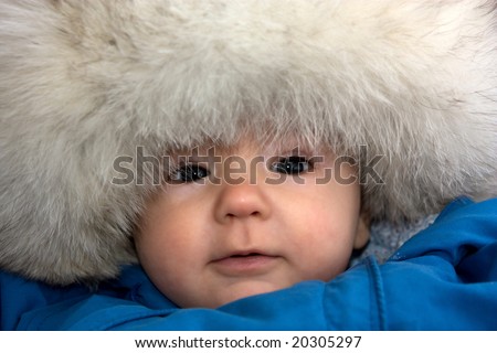 baby in big fur cap outdoors