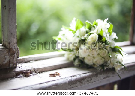 stock photo bouquet of white flowers and 2 wedding rings lying on an old