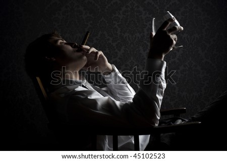 young man smoking cigar and drinking cognac at night