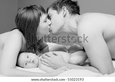 happy young parent kissing and daughter lying nearby