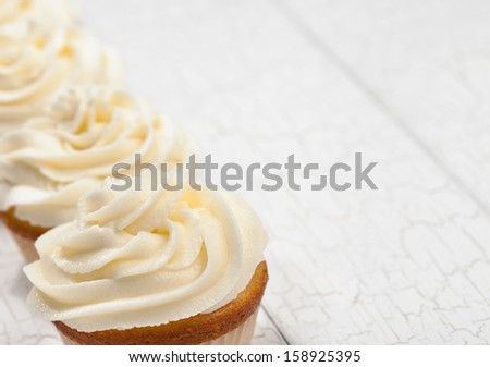 White vanilla cupcakes in a row. focus is on front cupcake.