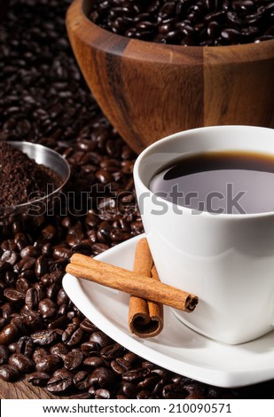 Close-up of Black Coffee in a white Coffee cup with whole and freshly ground beans. Dark background.