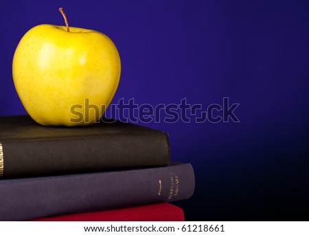 School Books stacked with an apple on top, a blue background and space on the right for your text.