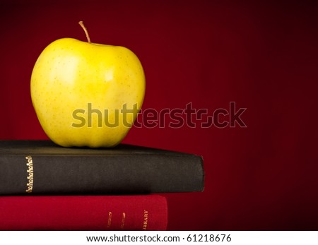 School Books stacked with an apple on top, a red background and space on the right for your text.