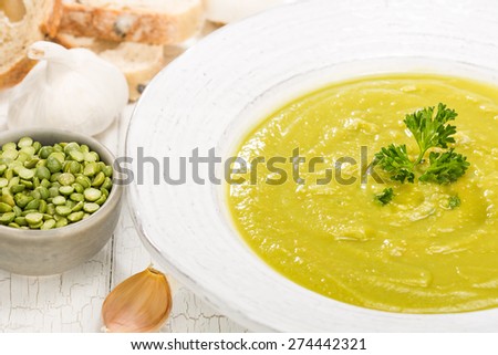 Close up of delicious homemade split pea soup with garlic, bread and parsley for garnish.