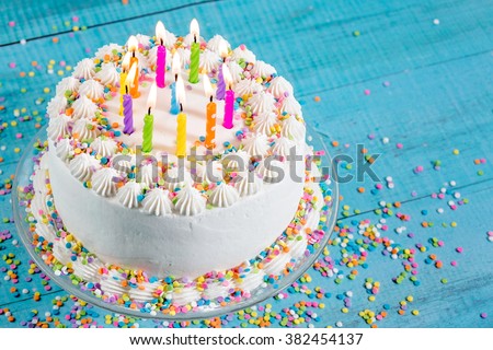 Birthday cake with colorful sprinkles and Candles over blue background