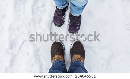 Man and woman stand opposite each other. Close up of feet in winter boots in the snow