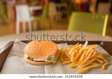 cheeseburger and french fries on the table. On the background of of fast food restaurants