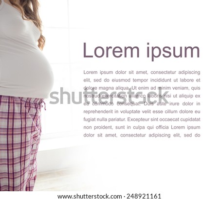 pregnant woman holding belly in white shirt and pink pajamas on white background