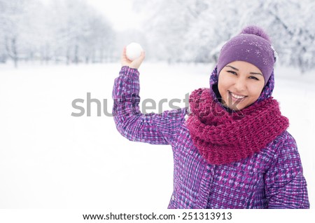 beautiful asian woman having fun on a snowy meadow.  The girl in the lilac hat purple jacket and pink scarf