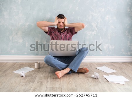 studenh holding his head with his hands. Around the scattered papers. Businessman gets stress