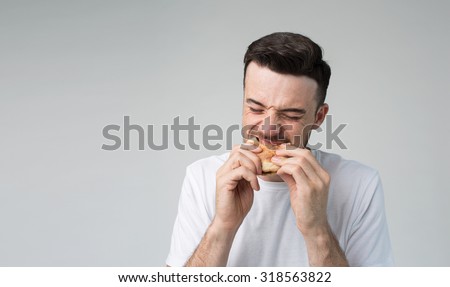 man holding a piece of hamburger. student eats fast food. not helpful food.  very hungry man