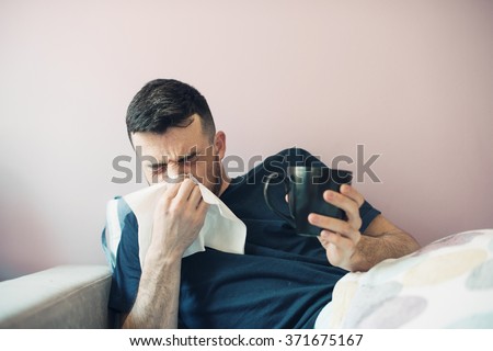 picture from a young man with handkerchief. Sick guy  has runny nose. man makes a cure for the common cold. The patient lies in bed